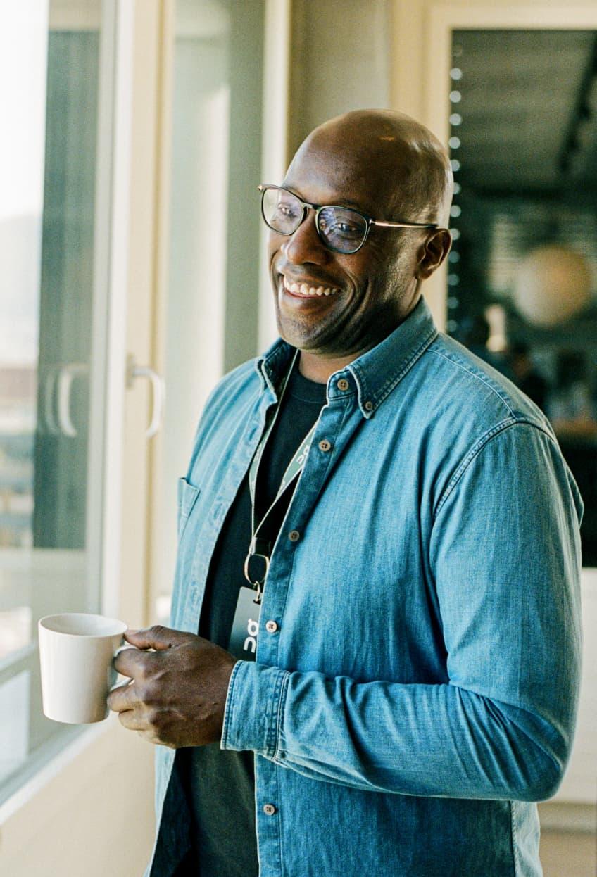 Man smiles and holds the cup of coffee
