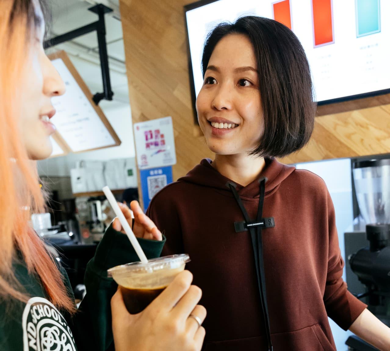 Woman drinking a cold coffee while talking to her friend