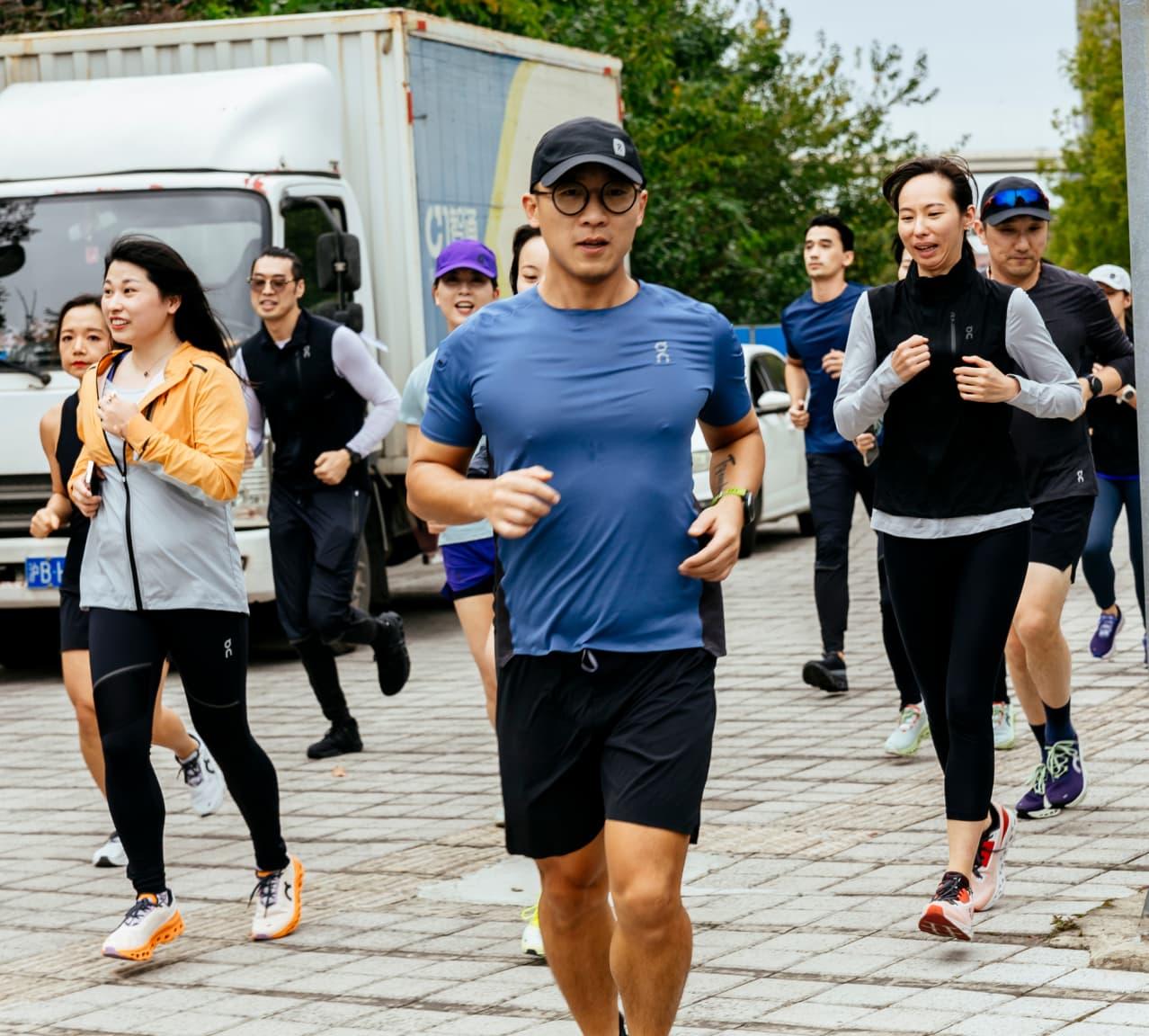 Man in a blue T-Shirt running with a group of runners behind him
