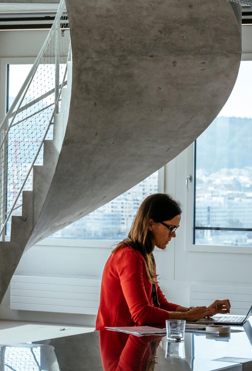 woman wearing red top working in modern concrete office